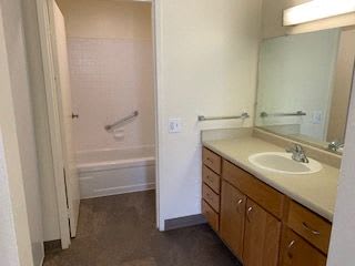 A bathroom with a sink, mirror, and bathtub.