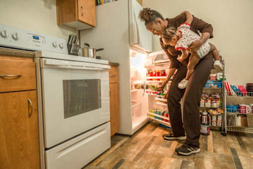 A woman holding a baby in a kitchen.