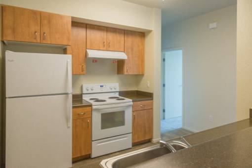 A kitchen with a white refrigerator, white oven, and wooden cabinets.