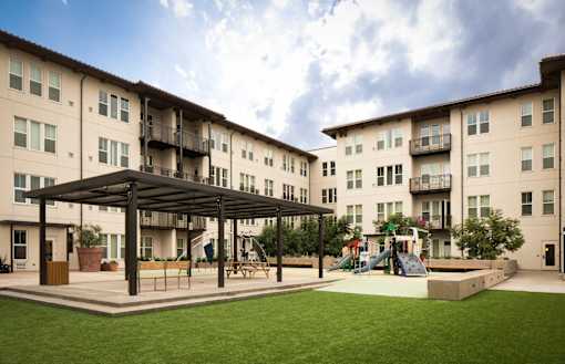 A playground area is located in front of apartment buildings.