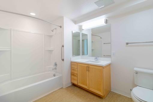 A white bathroom with a wooden cabinet and a white toilet.