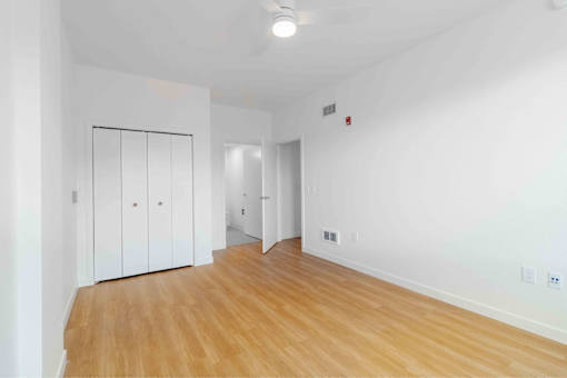 A room with white walls and wooden flooring, featuring a white wardrobe with a black frame.
