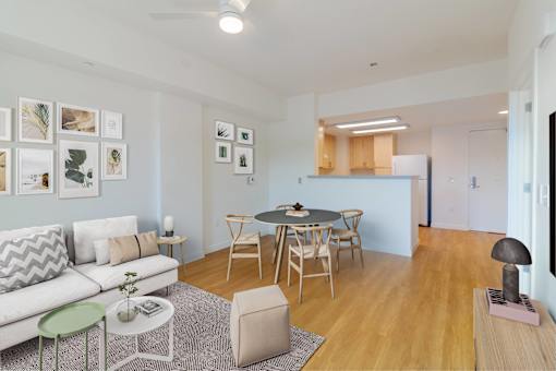 A living room with a white couch, a dining table with chairs, and pictures on the wall.