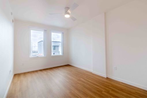 A room with wooden floors and two windows.