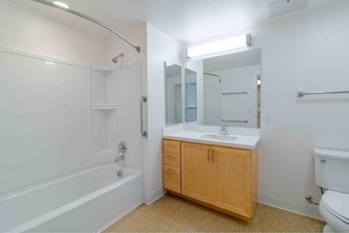 A white bathroom with a wooden cabinet and a white toilet.