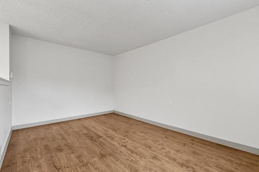 A room with wooden flooring and white walls.