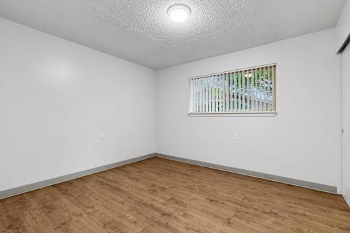 A room with a window and wooden flooring.
