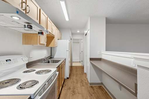 A kitchen with a white stove top oven and a white dishwasher.