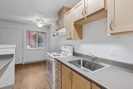 A kitchen with a stove, sink, and cabinets.