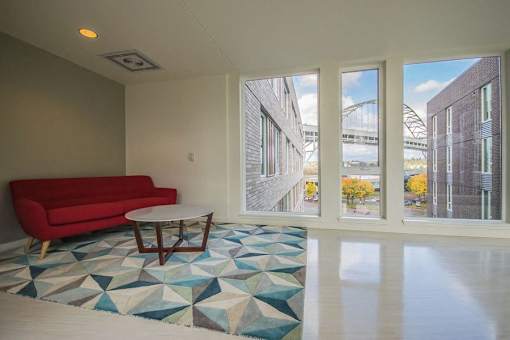 A red couch sits in a room with a geometric patterned rug.