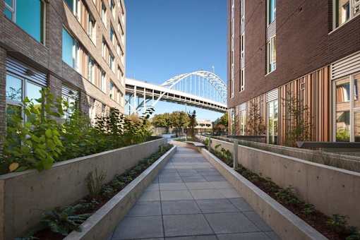 A walkway between two buildings with a bridge in the background.
