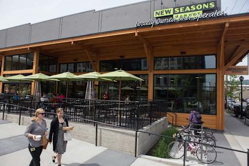 Two women walking in front of a New Seasons grocery store.