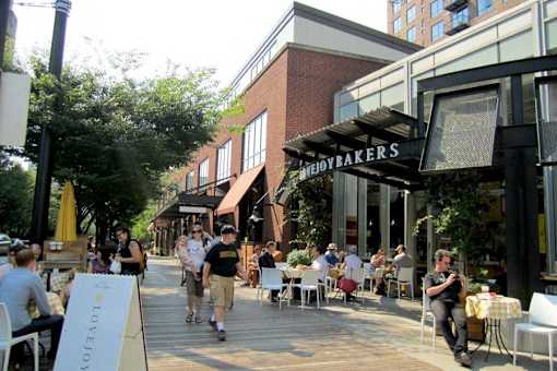 People are sitting at tables outside of a bakery.