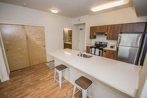 A kitchen with a white counter top and wooden floors.