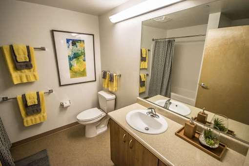 A bathroom with a toilet, sink, mirror, and towel racks.