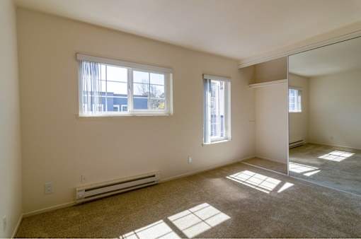 A room with a window and a carpeted floor.