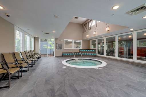 A spa room with a hot tub and lounge chairs.