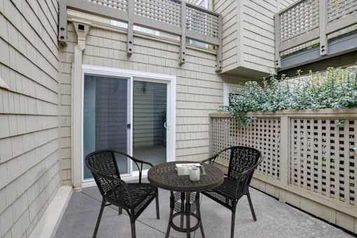 A patio with a table and chairs and a lattice fence.