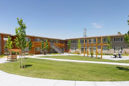 A large building with a lot of windows and a green lawn in front.