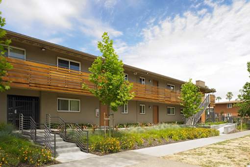 A row of townhouses with a sidewalk in front.