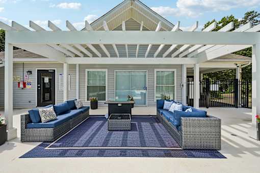 A patio with a white pergola and blue cushions.