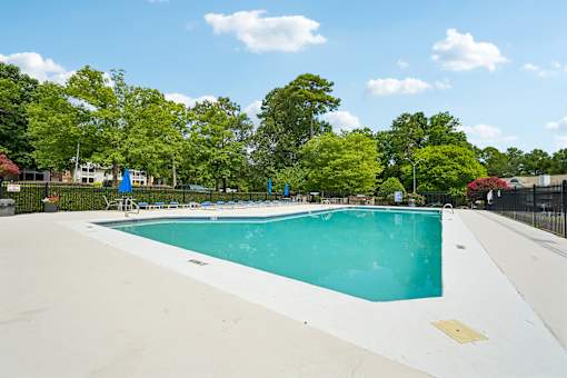 A large swimming pool surrounded by trees and a fence.