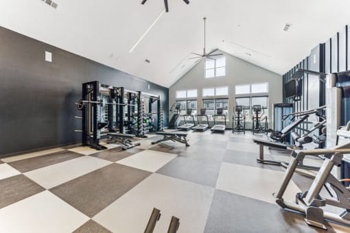 a gym with weights and cardio equipment in a building with windows  at Plat 4 at Research Triangle, North Carolina, 27703