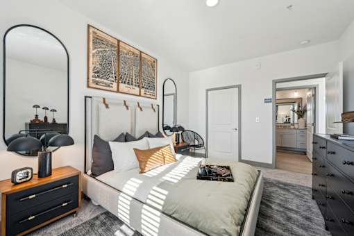A bedroom with a bed, nightstand, and a large mirror.