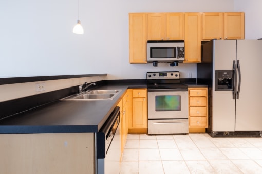 a kitchen with black countertops and wooden cabinets at 26 West, Managed by Buckingham Urban Living, Indianapolis