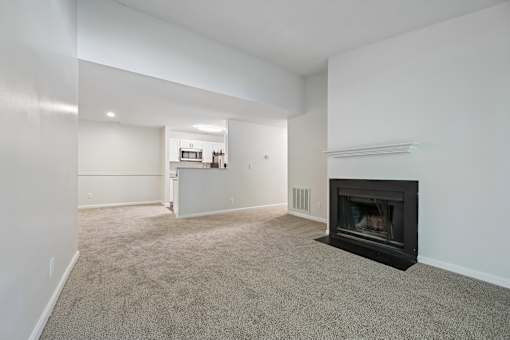 A living room with a fireplace and a carpeted floor.