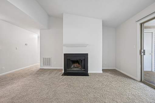A living room with a fireplace and carpeted floor.