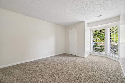 A room with a carpeted floor and a sliding glass door.