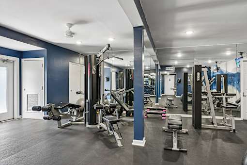 A gym with a variety of equipment including weights and benches.