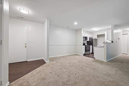 A spacious living room with a kitchen in the background.
