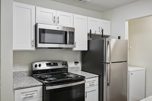 A kitchen with a black refrigerator, black stove, and white cabinets.