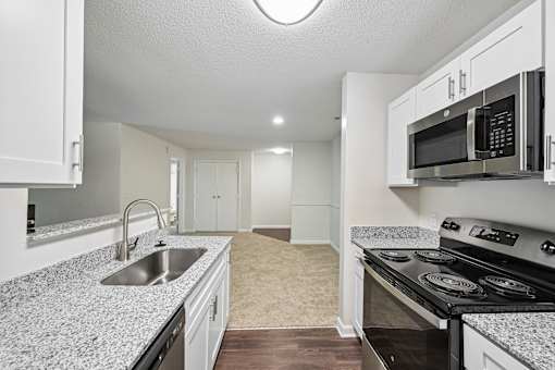 A kitchen with a stove, sink, and cabinets.