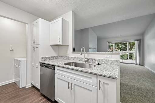 A kitchen with white cabinets and a granite countertop.