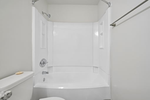 A white bathroom with a tub, toilet and sink.