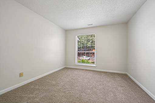 A room with a carpeted floor and a window.