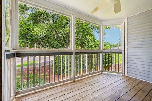 A screened porch with a wooden floor and white walls.