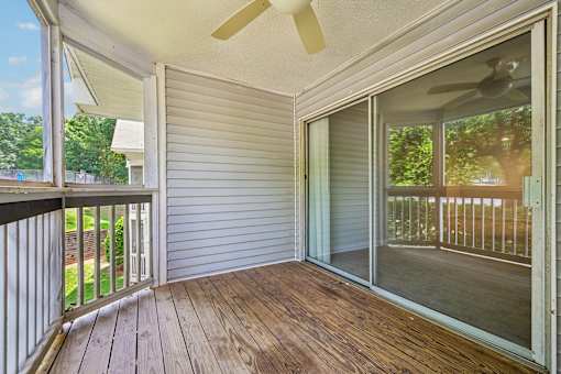 A sunny day on a wooden deck with a sliding glass door.
