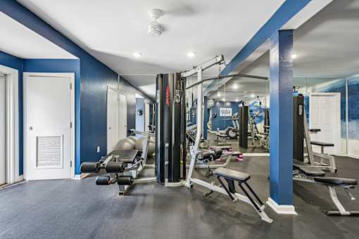 A gym with a row of treadmills and a row of exercise machines.