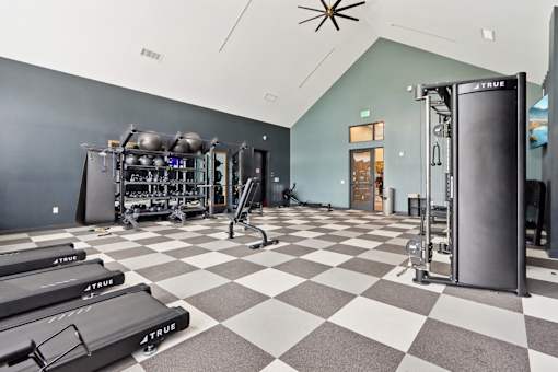 A gym with a checkered floor and a variety of equipment.