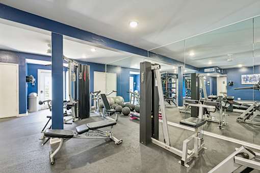 A gym with a variety of equipment including weights and weight machines.