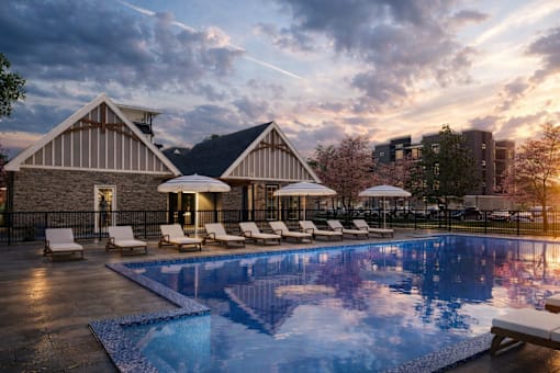 A large swimming pool in front of a house with sun loungers.