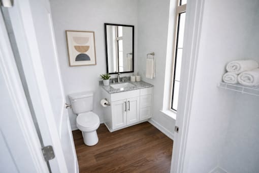 A white bathroom with a toilet, sink, and mirror.