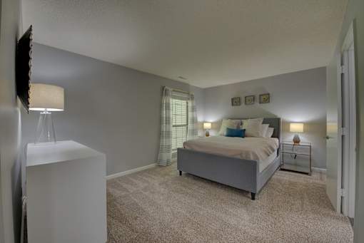 A bedroom with a bed, nightstand, and lamp.