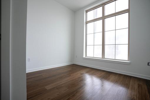 A room with a large window and wooden floors.