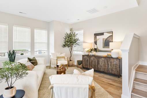 A living room with a white couch, a wooden coffee table, and a large painting on the wall.