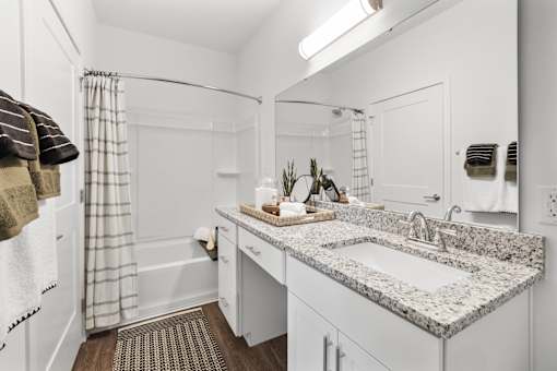 A bathroom with a marble countertop and a white sink.